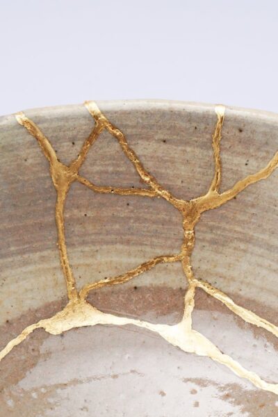 Close-up of repaired cracks in pottery, showcasing the art of Kintsugi and its golden seams that embrace imperfection and resilience