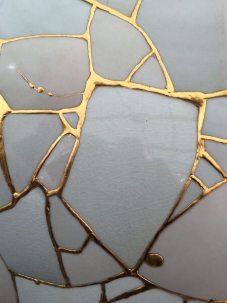 Close-up of repaired cracks in pottery, showcasing the art of Kintsugi and its golden seams that embrace imperfection and resilience